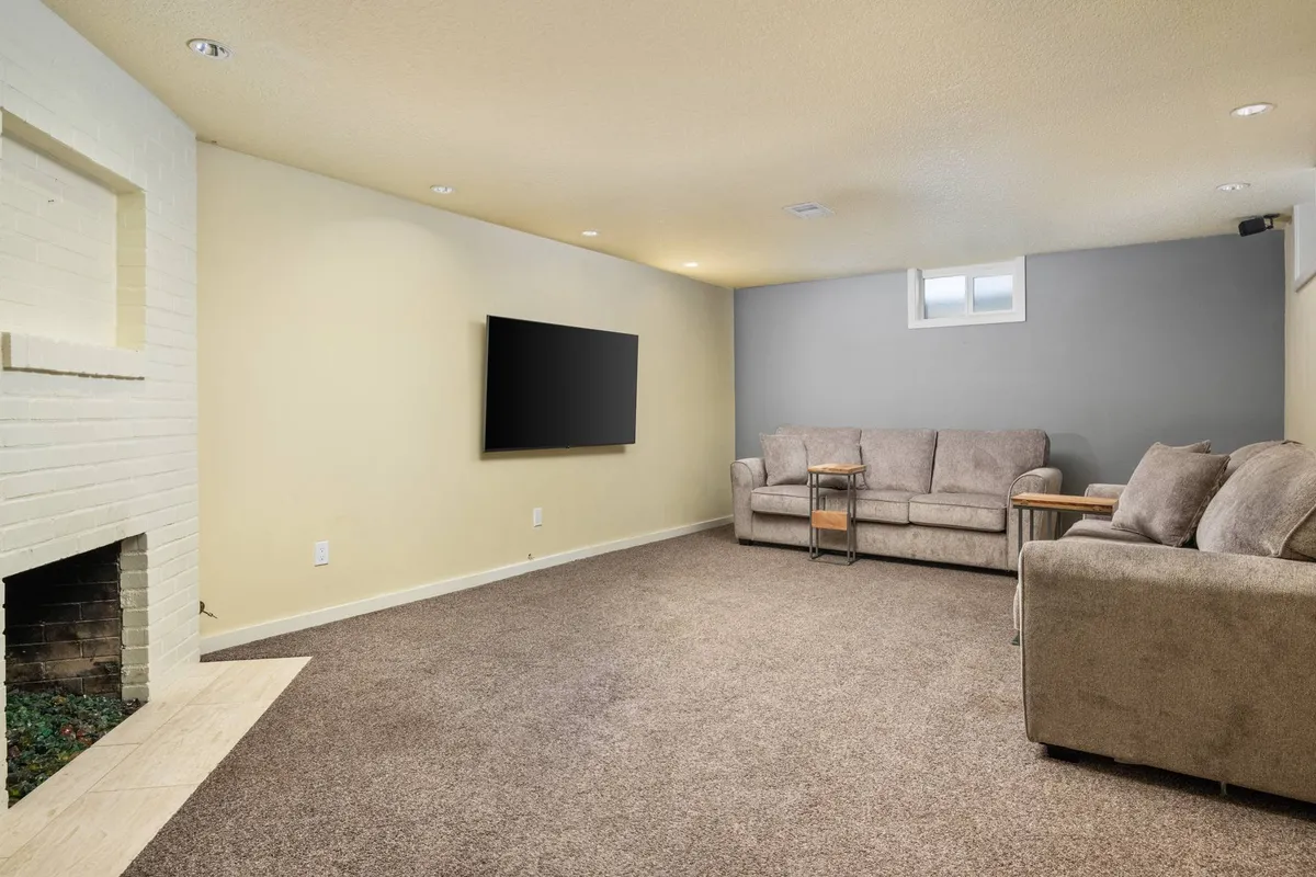 A cozy media lounge featuring comfortable sofas arranged for group seating, a television mounted on the wall, and a fireplace. The casual decor and inviting layout provide an ideal environment for movie nights or relaxing with friends and family.