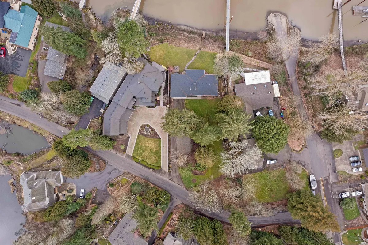 A peaceful neighborhood scene with a mix of houses, lush greenery, nearby water bodies, and roadways ideal for walking or biking. This broader perspective suggests off-property exploration opportunities like nature walks or riverside adventures.