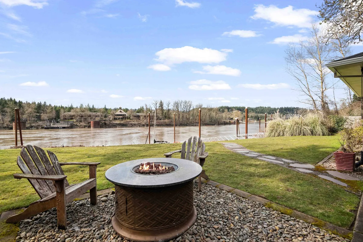 A welcoming outdoor fire pit area with Adirondack chairs arranged to face the river, creating a cozy spot for gathering, storytelling, and enjoying the tranquil riverside environment.