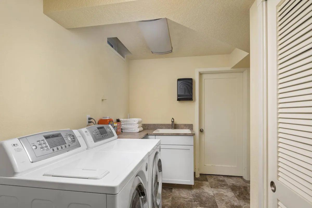 A tidy laundry area with a washing machine, dryer, sink, and a dedicated folding area. The space is organized and practical, underscoring the home's convenience for longer stays.