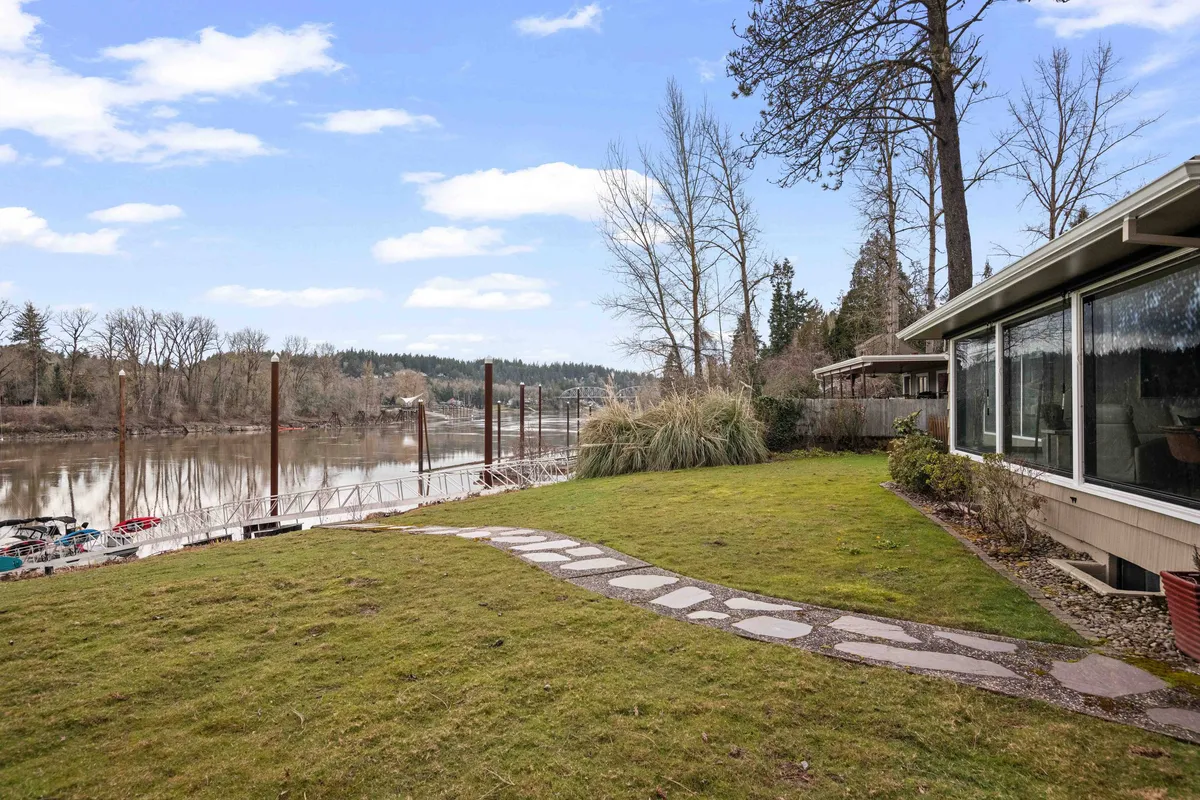 A peaceful view of the Willamette River with a winding pathway and surrounding trees, inviting leisurely strolls, fishing, or simply soaking up the tranquil natural beauty of the area.